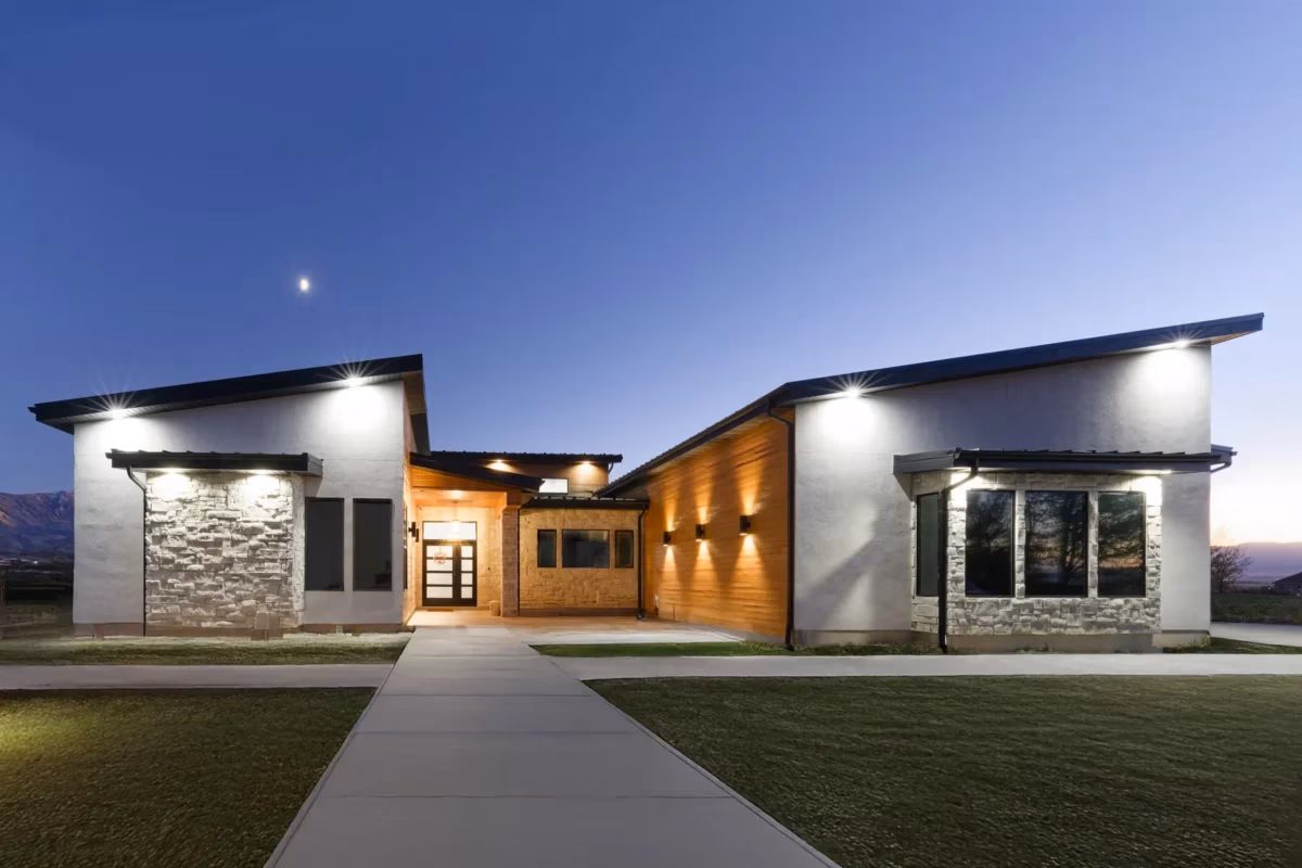 Modern custom home exterior at dusk with warm lighting and sleek white stucco design.